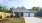 a blue house with a patio, lawn and driveway